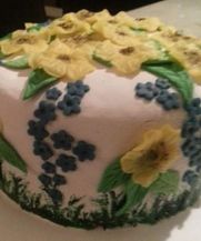 Een taart vmet de hand gemaakte bloemen en geschilderd gras